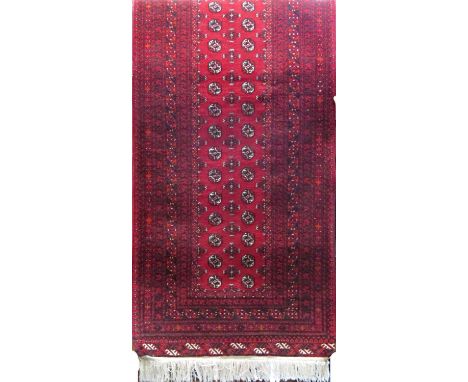 A Turkoman design carpet with a central panel of guls on a predominantly red ground, 280cm x 100cm 