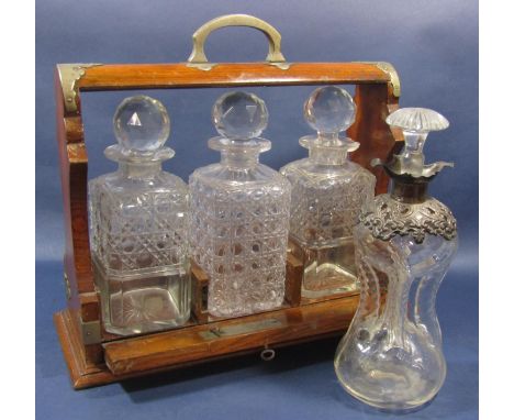 An Edwardian oak tantalus with a pair of decanters and a third decanter with an all over hobnail design, with key, and anothe