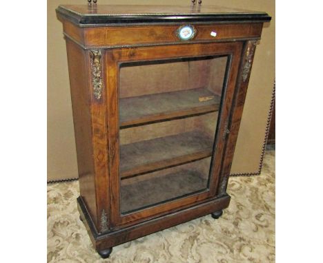 A Victorian walnut and figured walnut veneered pier cabinet, enclosed by a rectangular glazed panelled door, with two velvet 