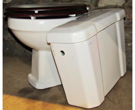 A white glazed ceramic toilet with chrome pipe and flush box cistern and fittings 