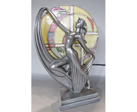 An Art Deco style lamp of a woman posing in front of a circular stained glass window. 