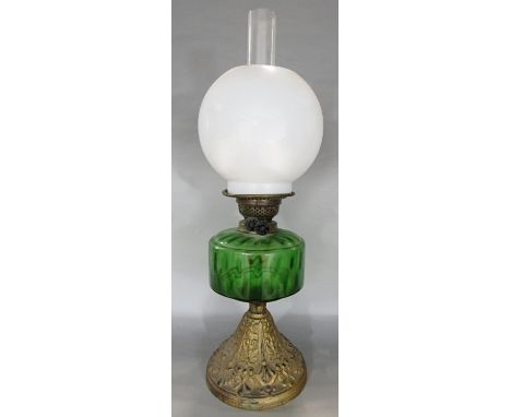 A 19th century oil lamp with a green glass font raised on a gold painted flared base. 56cm high. 