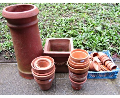 A terracotta chimney pot of cylindrical and slightly tapered form together with approximately 60 terracotta flower pots of va