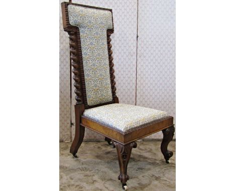 A Victorian low nursing or prayer chair with repeating floral patterned upholstered seat and T shaped back within a walnut sh