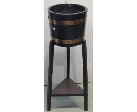 An R A Lister jardinière in oak with copper bands raised on a tripod base 