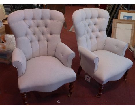 A pair of contemporary spoon back arm chairs with stone linen button back upholstery raised on turned legs and castors