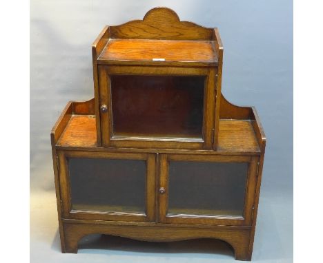 An early 20th Century Art and Crafts oak bookcase with one glazed door above two further glazed doors raised on bracket feet,