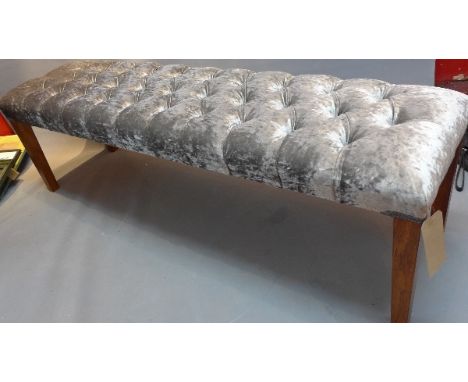 A contemporary window stool with purple velour button down upholstery raised on tapered mahogany legs, H:45cm W:150cm D:39cm 
