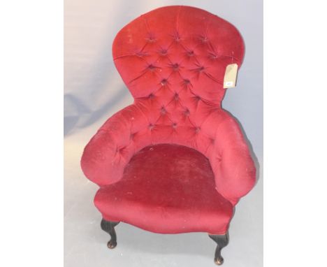 An early 20th Century spoon back armchair with red velour button back upholstery raised on cabriole legs