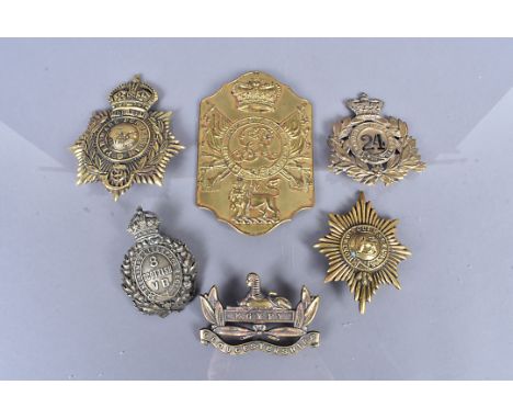 A small collection of helmet plates and badges, to include a Victorian British Officer's Stove Pipe Shako plate, a Victorian 