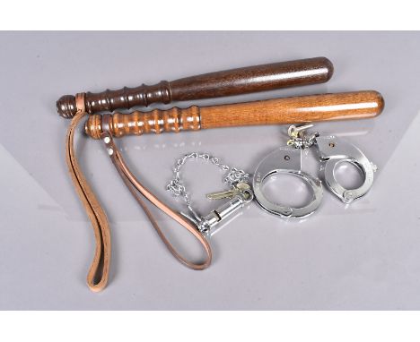 Two late 20th Century turned wooden truncheons, one dark wood, the other slightly lighter, both with leather straps, together
