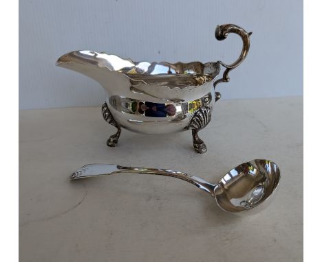 A George V silver sauce boat with wavy rim border, scroll handle and shell capped pad feet by Edward Barnard &amp; Sons Ltd, 