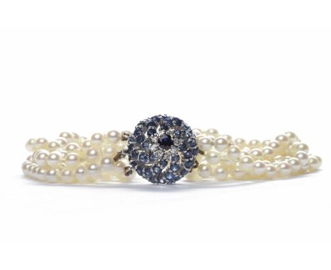 FOUR STRANDED PEARL BRACELETformed by rows of spherical white pearls each approximately 4.50mm diameter, with a blue gem and 