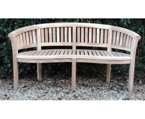 A TEAK GARDEN BENCH of curved form with a slatted back and seat and square legs 156cm wide 