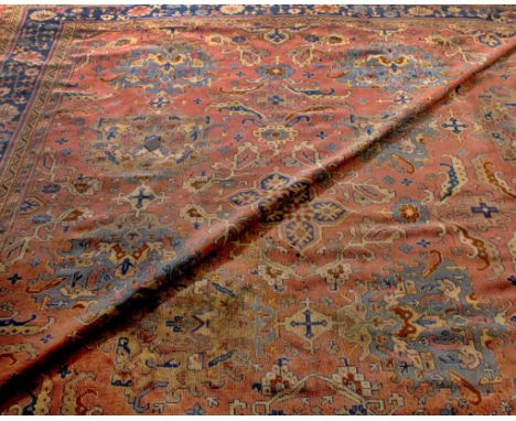 A LARGE EARLY 20TH CENTURY MIDDLE EASTERN PINK AND BLUE GROUND CARPET with multiple stylised motifs and a geometric foliate b