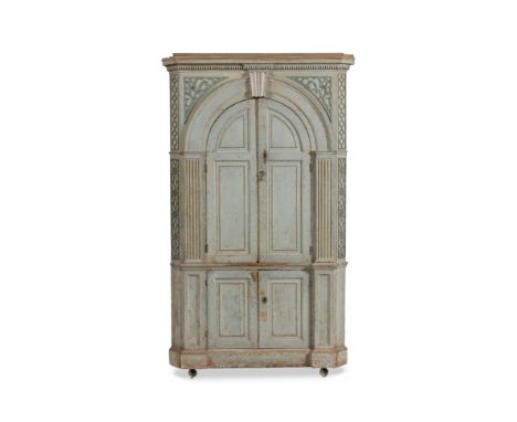 A GEORGE III LIGHT BLUE PAINTED PINE CORNER CUPBOARD with dentil cornice, blind fretwork decoration above the arching twin pa