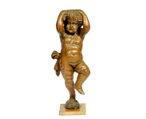 AN ANTIQUE CARVED PINE FIGURE OF A CARYATID PUTTO with his arms to his head, wearing a sash and standing on one foot, mounted
