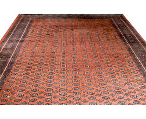 A MID TO LATE 20TH CENTURY PAKISTANI RED GROUND CARPET with eleven rows of  guls and a multiple banded border, 385cm x 530cm 