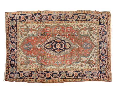 A HERIZ CARPET with a central large blue ground medallion in a rust field of scrolling flowers and within a wide herati borde