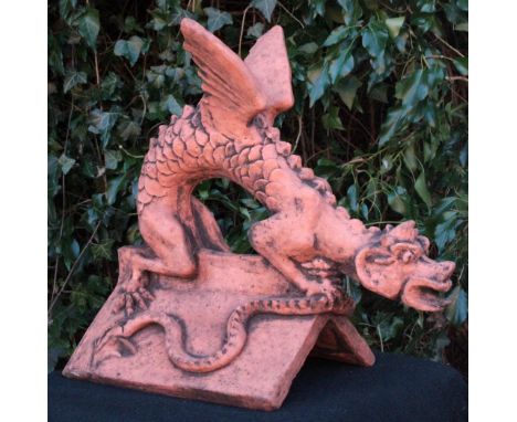 A CAST TERRACOTTA DRAGON ROOF RIDGE FINIAL of a dragon crouching on a triangular ridge tile 51cm long x 47cm high