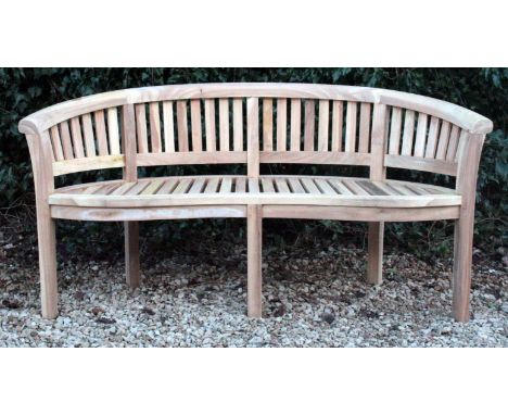 A TEAK GARDEN BENCH of curved form with a slatted back and seat and square legs 156cm wide 