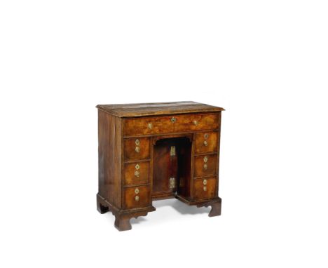 A GEORGE I WALNUT KNEEHOLE DESK fitted with an arrangement of seven herringbone banded drawers around a recessed cupboard, th