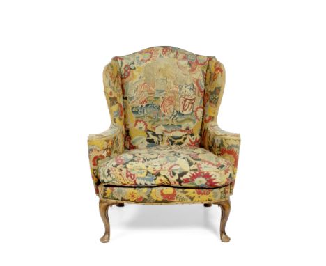 A GEORGE II STYLE WING BACK ARMCHAIR with antique tapestry covers, the cabriole legs terminating in pad feet, 89cm wide