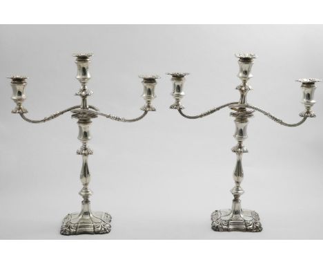 A PAIR OF EDWARDIAN THREE-LIGHT CANDELABRA on shaped square bases with shell decoration at the corners, spool-shaped capitals