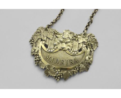 BY PAUL STORR:- A George III cast silvergilt wine label in the form of a lion's pelt and mask with fruiting vines and a matte