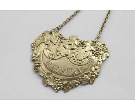 BY PAUL STORR:- A George III cast silvergilt wine label in the form of a lion's pel &amp; mask with fruiting vines and a matt