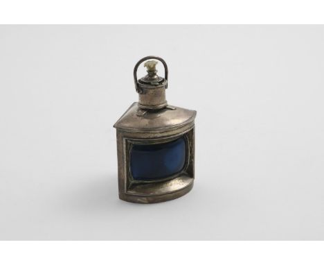 AN EDWARDIAN NOVELTY SPIRIT LIGHTER in the form of a ship's lamp with a swing handle and a curved, blue glass lens, by L. Emm