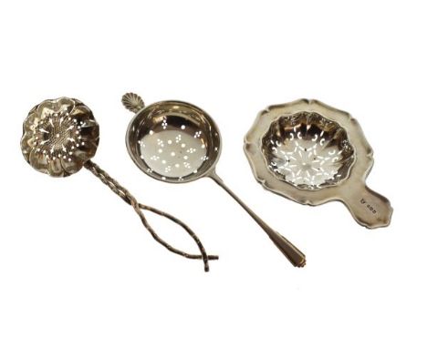 Two silver tea strainers, the first George V, London 1916, the second Elizabeth II, Birmingham 1964, together with a white me