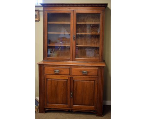 Early 20th Century walnut bookcase on cabinet, the upper stage having a dentil cornice and pair of glazed doors enclosing thr