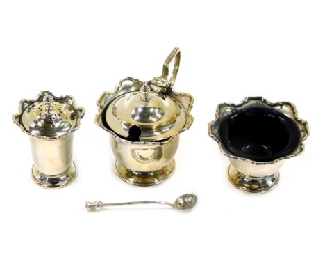 A George V and later silver three piece cruet set, comprising mustard, salt and pepper, two with blue glass liners, and a lat