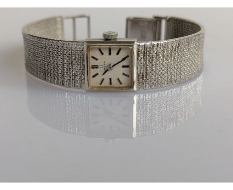 A vintage Omega ladies manual wristwatch with square dial, baton markers on a white gold case, textured strap and deployment 