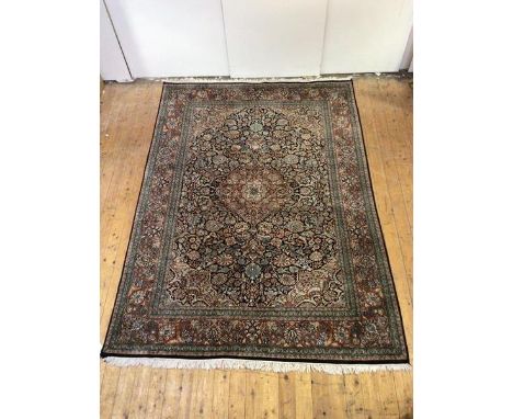 A hand-knotted carpet of North-West Persian design, the black field with central medallion and entwined flowers and foliage, 