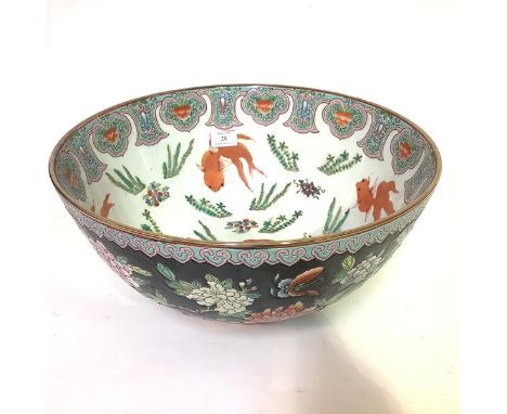 A large Chinese famille noir porcelain punch bowl, the interior painted with carp amidst fronds, the exterior with butterflie