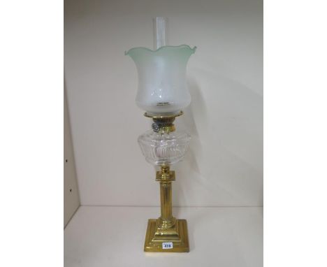 A brass oil lamp with clear glass reservoir and green tinted shade, 67cm tall, in good condition and no obvious damage 