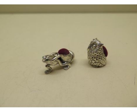 A sterling silver owl pin cushion and a sterling silver frog with glass eyes towing a snail shell pin cushion, 3cm long, both