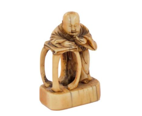 18th/19th century Japanese carved ivory netsuke of a figure in robes resting on a table, 4cm long