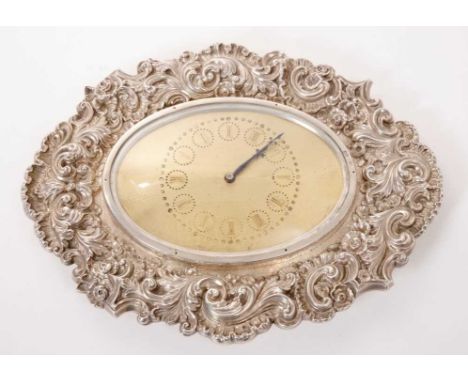 Victorian silver mounted dressing table clock, with an oval gilt dial with engine turned decoration, mounted in a heavy scrol