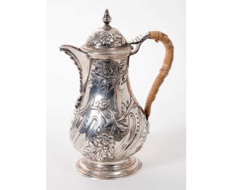 Late Victorian silver hot water jug of baluster form, with embossed wrythen and floral decoration, rattan covered handle and 