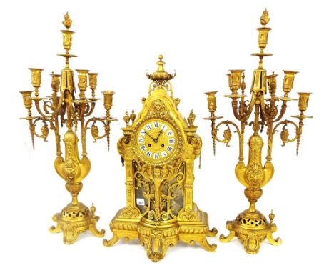 Large decorative gilt metal two train mantel clock garniture striking on a bell, the 5" repousse dial with Roman cartouche en