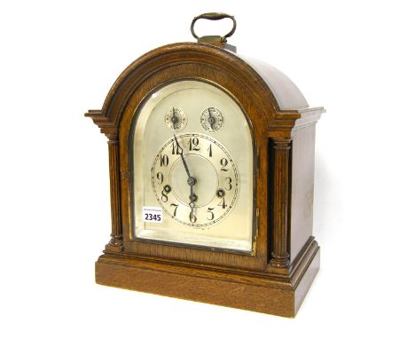 German oak three train bracket clock, the Junghans movement chiming on five rods, the 6" silvered arched dial with subsidiary