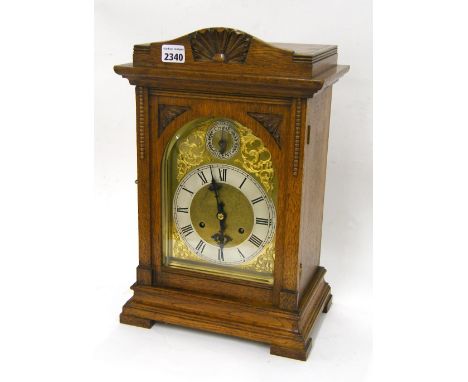 German oak three train mantel clock striking on five rods, the 7" brass arched dial with chime/silent subsidiary dial to the 