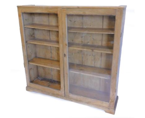 A pine bookcase, with two doors, one glazed, on bracket feet, 137cm H, 143cm W.