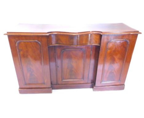 A Victorian mahogany sideboard, the moulded edge above a central serpentine shaped drawer, above a door with an arched panel,