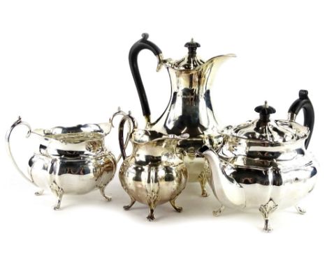 A George V silver four piece tea service, each piece with G shaped body, the teapot and hot water pot with ebonised knop and 