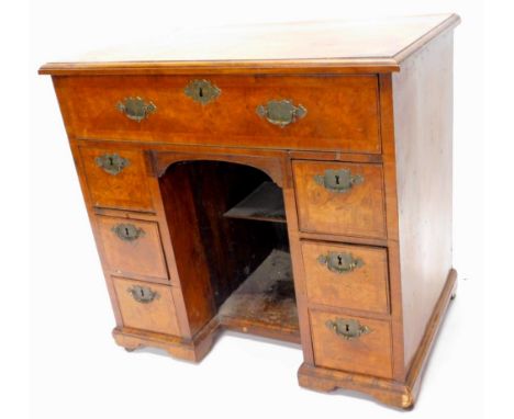 A walnut kneehole desk or dressing table, the rectangular quarter veneered top with a feather and cross banded border above a