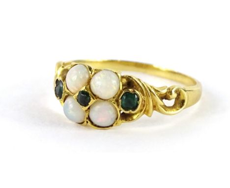 An opal and emerald ring, in floral cluster, with four opals and three rough cut emeralds, in rub over setting, with scroll a